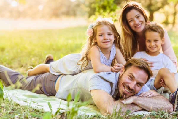 Attractive young family posing lying down on a sunny summer day in nature